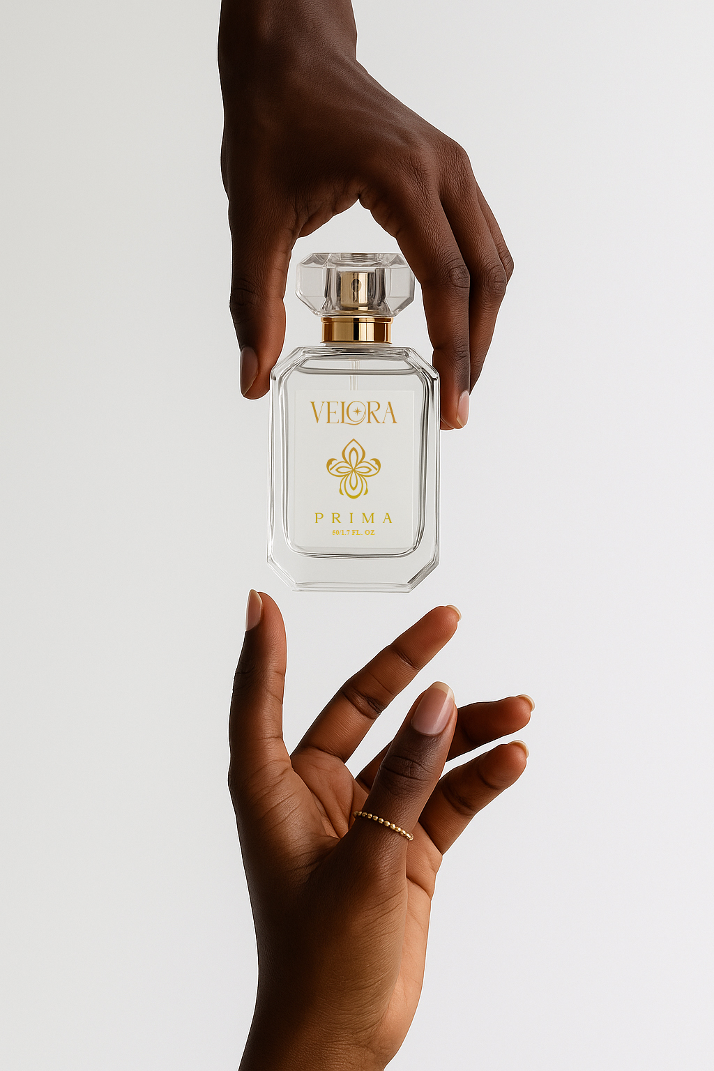 Velora Prima luxury eau de parfum bottle held between two hands against a white background, showcasing elegant glass design and gold logo.