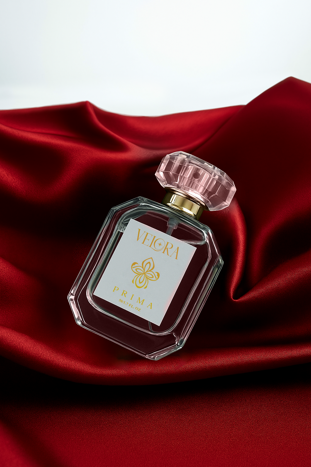 Velora Prima luxury eau de parfum bottle displayed on rich red silk fabric, highlighting its elegant glass design and gold floral logo.