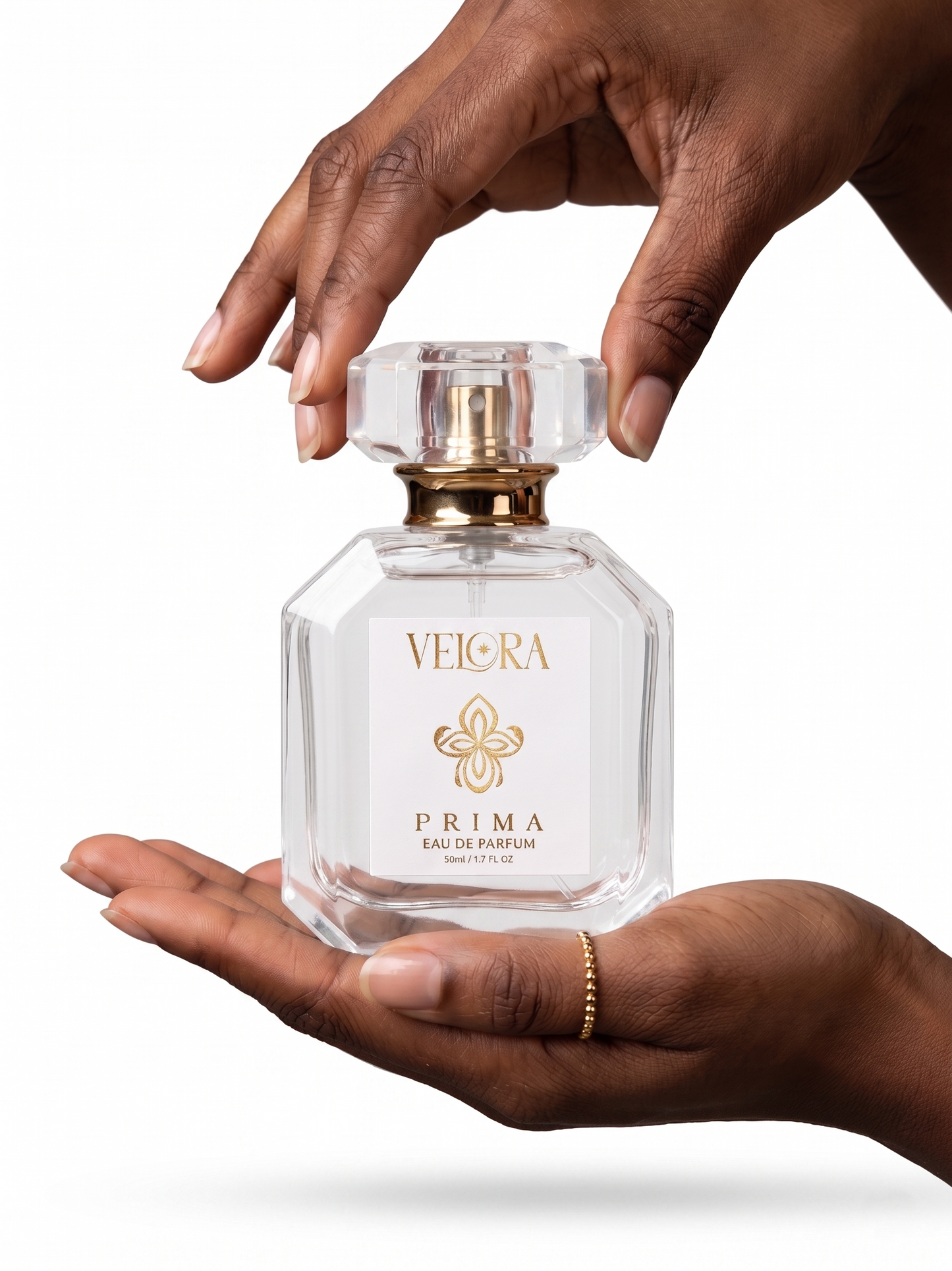 Hand holding a Velora Prima perfume bottle against a white background